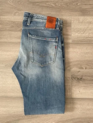 Replay Jeans - Snygga blå jeans från Replay med klassisk femficksdesign och läderpatch bak i midjan. Jeansen är i mycket bra skick. Modell Anbass. Storlek 32/32! Hör av dig 🤙 