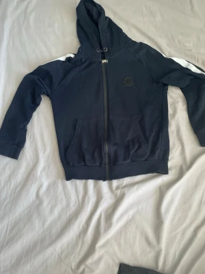 Mörkblå Moncler hoodie med dragkedja - Snygg mörkblå hoodie från Moncler. Inga skador eller fläckar.QR koden funkar.Hör av er vid minsta fråga!