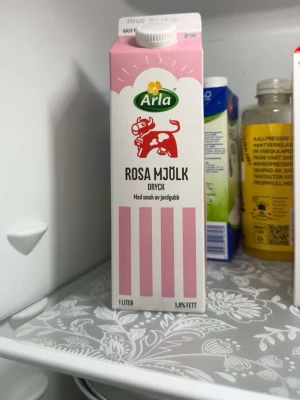 Arla rosa mjölk med jordgubbssmak - En 1-liters förpackning rosa mjölkdryck från Arla med smak av jordgubb. Kartongen är rosa och vit med en tecknad ko på framsidan. Innehåller 1,0% fett och har en klassisk skruvkork på toppen. Den som köper den kan även få den ursköljd och ren, om så önskas!