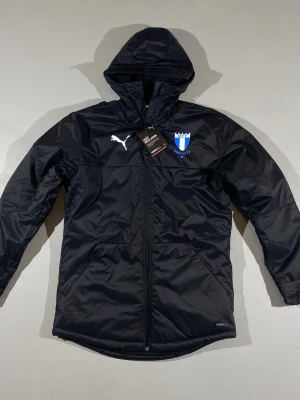 Svart pufferjacka Malmö FF Puma S & XS  - SLÅ TILL! (Pris flexibelt vid snabb affär) Svart pufferjacka från Puma med Malmö FF logga på bröstet och vit Puma logga till extremt bra pris. Jackan har huva, dragkedja och värmeisolerande WarmCell-material. Finns i storlek S & XS