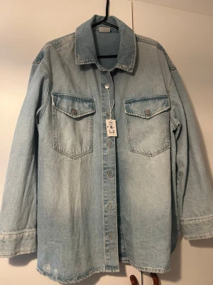 Ljusblå jeansjacka från Vailent - Snygg ljusblå jeansjacka från Vailent med klassisk krage, två bröstfickor med lock och knappar framtill. Jackan har raka ärmar och en avslappnad passform, perfekt att slänga över en hoodie eller t-shirt. Tidlös modell i 100% denim.
