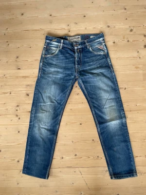 Blå jeans från replay - Säljer ett par klassiska blå jeans från replay med snygga slitningar och tvättade detaljer. raka ben och normal midja. Perfekta för en avslappnad och trendig look. Stork 29 32
