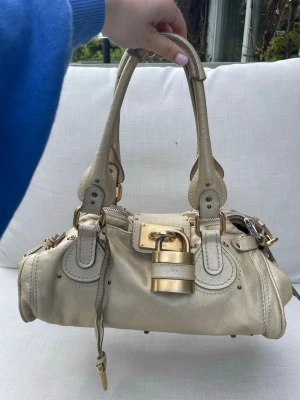 Chloé Paddington beige handväska - Säljer min fina Chloé Paddington handväska i beige läder med dubbla handtag och stora guldfärgade metalldetaljer. Väskan är vintage från tidigt 2000-tal, vilken gör den unik, och i bra skick för å va nästan 20 år gammal.💞💞
