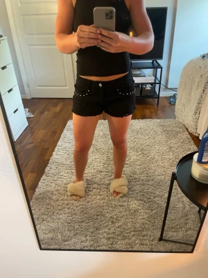 Svarta jeansshorts med nitar - Snygga svarta jeansshorts med nitar längs fickorna. Perfekta för sommaren och passar till allt. Sköna och trendiga shorts. Använda ett fåtal gånger och finns inget tecken på slitage💕Skriv vid frågor/funderignar. 