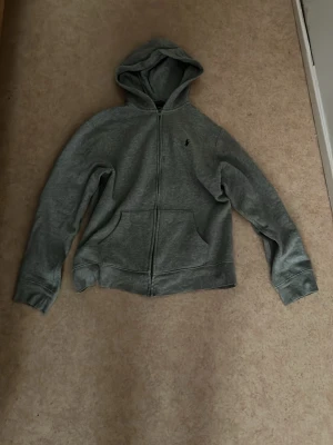 Grå hoodie från Polo Ralph Lauren - Grå Polo zip-up, snygg och skön passform. Väldigt stilren och lätt att matcha. Passar ca 160–170 cm. Bra skick och perfekt till både vardag och finare outfit. Säljes till bra pris, först till kvarn! Ny pris 2200! ✨