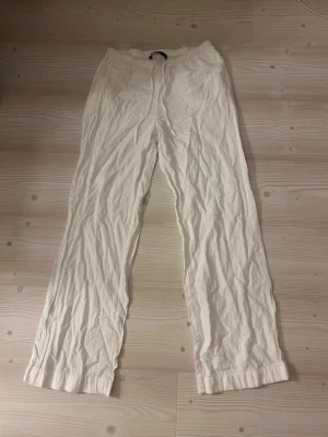 Vita vida linnebyxor - Snygga och luftiga vita linnebyxor med rak passform och resår i midjan. Perfekta för en avslappnad och stilren look. Byxorna har en klassisk design och är tillverkade i 100% linne för maximal komfort.