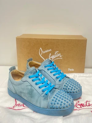 Louis Junior Spikes - Ljusblåa sneakers med nitar från Christian Louboutin. Fint skick, nån fläck i mockan på något ställe annars riktigt bra. Kommer med allt og, dvs orginallåda, dustbags och extra snören.