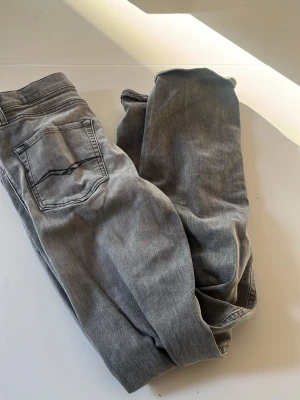 Grå jeans från Replay - Snygga grå jeans från Replay med klassisk femficksmodell och diskret tvättad look. Jeansen har raka ben och normal midja, tillverkade i mjukt denimtyg som ger en bekväm känsla. Perfekta för dig som gillar en avslappnad men stilren stil. Scick 8/10 då det finns tecken på användning. Priset är ej hugget i sten och hör av er vid funderingar 