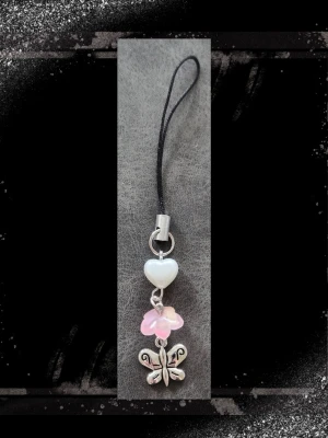 Phone Charm - Rosa, Vit & Silver - En kortare silvrig mobil dekoration att sätta i de 2 hålen som finns på de flesta mobilskal. Somrigt vårtema, med ett vitt hjärta, rosa blomma och en fjäril.   Längd är ca 9 cm. (Bild 2) Bild 4 visar lite hur man kan använda den och hur den hänger från ex telefon eller om man sätter den på en termos.   Handgjort av mig  ✨BUNDLE REA✨  Frågor? Skicka bara. Kolla noggrant innan köp. Klicka in på fotona. Returer av smycken är inte godkända pågrund av hygienskäl.