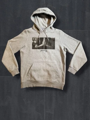 Grå hoodie med tryck och ficka - Snygg grå hoodie från Friary med svartvitt tryck på bröstet och text. Utrustad med huva och dragsnören samt en stor magficka. Perfekt för en avslappnad och trendig stil.