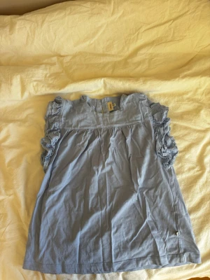 Blå blus - Säljer denna fina blus från pomp de lux. Inget fel på den och ser helt ny ut. Den är mellanblå och har fina detaljer på ärmarna 
