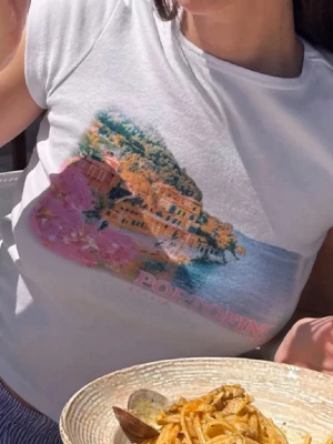 Nyskick subdued Vit croppad t-shirt med Portofino-tryck Stl s - Snygg vit croppad t-shirt med färgglatt Portofino-tryck framtill. T-shirten har rund halsringning och korta ärmar, perfekt för en avslappnad och trendig look. Materialet känns mjukt och bekvämt mot huden.