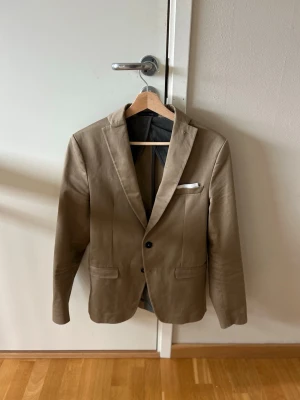 Beige kavaj Zara  - Snygg beige kavaj från Zara Man som passar S. Storleken är 46 men passar snarare 44. Tillverkad i ett lätt material, perfekt för en stilren look nu på sommaren!. Fint skick och rolig färg!