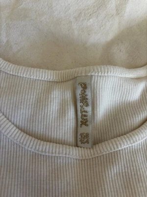 Vit ribbad topp från Pomp de lux - Säljer denna ribbade vita t shirten. Väldigt fin och bra för layering. Har varit en favorit länge och passar perfekt till sommaren 
