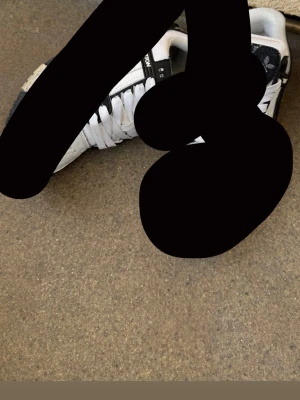 Nike Air Jordan 1 Mid svart/grå - Snygga Nike Air Jordan 1 Mid sneakers i svart och grått med klassisk röd Jumpman-logga på plösen. Skorna har svart Swoosh, svarta skosnören och perforerad tå. Perfekta för dig som gillar streetwear och vill sticka ut med en ikonisk modell.