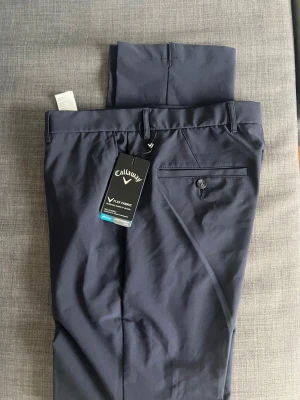 Callaway Golfbyxor—Oanvända - Snygga mörkblå golfbyxor från Callaway. Helt oanvända har bara legat i garderoben då de var för stora. Storleken är 32-34. Pris går att diskutera