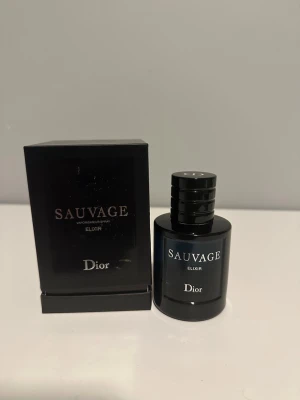 Dior Sauvage Elixir parfym - Dior Sauvage Elixir är en exklusiv herrparfym i en elegant, mörkblå glasflaska med svart lock. Flaskan har en stilren och lyxig design med vit text. Kommer med originalkartong. Perfekt för dig som gillar intensiva och maskulina dofter.