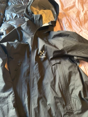 Svart vindjacka från Haglöfs - Svart vindjacka från Haglöfs med huva i herr storlek