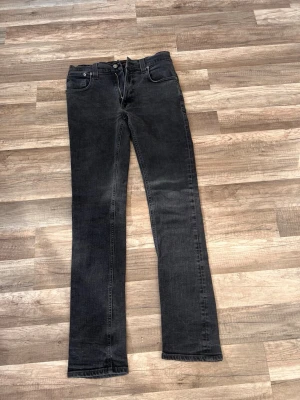 Svarta nudie jeans  - Svarta Nudie Jeans Thin Finn i nyskick 🖤  Säljer ett par stilrena svarta Nudie Jeans i modellen Thin Finn. Slim fit med smal passform som sitter snyggt – perfekt till både vardag och fest.  • Färg: Svart   • Storlek: 33/34   • Modell: Thin Finn   • Skick: Nyskick