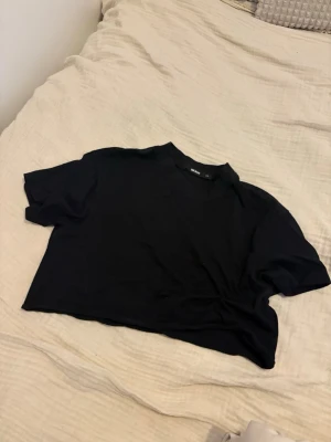 Svart cropped t-shirt från Bik Bok - En svart cropped t-shirt från Bik Bok med rund hals och korta ärmar. T-shirten har en enkel och clean design, perfekt att matcha med höga jeans eller kjol. Tillverkad i mjukt bomullsmaterial för en bekväm känsla. Jättefin enkel tröja som använt fåtal gånger och i ett bra skick. Kom med egna bud eller kontakta vid intresse