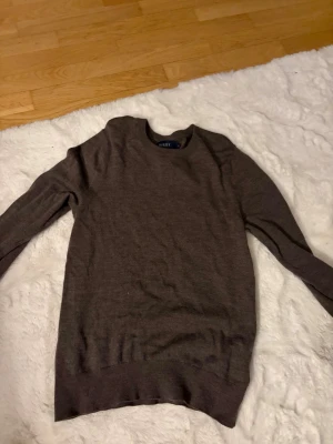 Brun stickad tröja  - Mjuk och stilren brun stickad tröja . Tröjan har rund halsringning, långa ärmar och ribbade muddar vid ärmslut och nederkant. Perfekt för lager på lager och enkel att matcha med olika outfits.