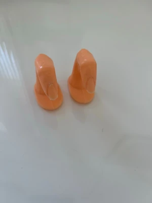 Plastfingrar för nagelövning - Två stycken plastfingrar i beige färg, perfekta för att öva på nageldesign, nagelteknik eller applicering av lösnaglar. Fingrarna har en realistisk form och platt botten för stabil placering på bordet. Tillverkade i tålig plast.