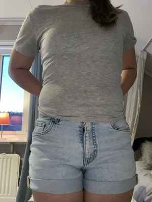 Ljusblå denimshorts med uppvik - Säljer ett par ljusblå denimshorts med uppvikta benslut och klassisk femficksdesign. Shortsen har normal passform och stängs med dragkedja och knapp. Perfekta för varma dagar och enkla att matcha med olika toppar.