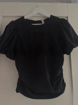 Svart puffärm topp  - Snygg svart topp med puffärmar och fina detaljer på ryggen. Storlek 34. Fint skick, använd 1 gång💓Redo att skickas direkt📦