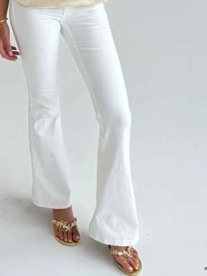 Vita bootcut jeans - Säljer ett par vita bootcut jeans med hög midja och utsvängda ben. Jeansen har klassisk femficksdesign och är tillverkade i ett stretchigt denimtyg som sitter snyggt. Perfekta för en fräsch och trendig look.