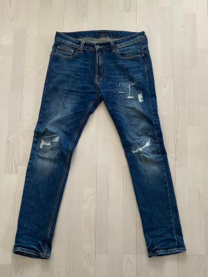 Nudie Jeans  - Tjena! Säljer nu dessa Nudie Jeans med en riktigt sjuk tvätt och tvär snygga slitningar. Storlek 34/32 och i väldigt bra skick. Priset är ej hugget i sten så hör av dig vid minsta fundering:)