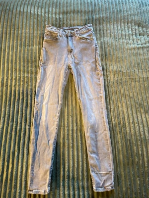 Gråa jeans - Säljer ett par gråa jeans med klassisk femficksdesign och dragkedjegylf. Jeansen har smal passform och raka ben, perfekta till en avslappnad stil. Materialet är mjukt denim som ger en bekväm känsla hela dagen. W28 L30