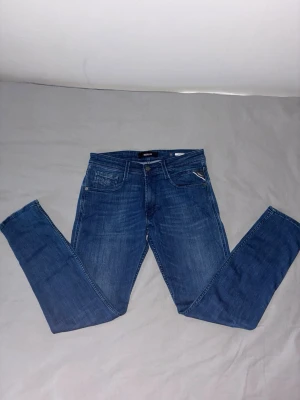 Blå Replay jeans - Säljer ett par klassiska Replay anbass jeans med fem fickor och dragkedja. Jeansen har en snygg tvätt och är tillverkade i stretchigt denim för en bekväm passform. Perfekta för dig som gillar en trendig stil. Mitt pris (349kr) nypris (1100kr)