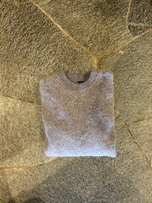Grå/lila stickad tröja i ullmix - Mysig grålila stickad tröja med rund halsringning och långa ärmar. Tröjan har en enkel, klassisk design och är tillverkad i mjuk ullmix som känns skön mot huden. Tröjan är ganska liten i passformen. Ny pris: 549, mitt pris: 199