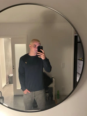 Mörkblå tröja från pier one - Snygg mörkblå långärmad tröja från pier one med den klassiska gula loggan broderad på bröstet. Tröjan har en enkel och stilren design med rund halsringning och mjukt material som passar perfekt till jeans.