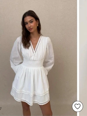 Vit kortklänning från Nelly - Supersöt vit kortklänning från Nelly med v-ringning, långa puffärmar och smockad midja. Klänningen har volangdetaljer och spets längs kanterna för en romantisk vibe. Perfekt för sommarens alla tillfällen och särskilt studenten! Säljer då jag missade returdatumet. Nypris: 499kr. Mitt pris: 400kr (kan diskuteras vid snabb affär)💜