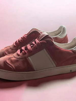 Rosa valentino flycrews  - Snygga sneakers i rosa mocka med vita detaljer och vita skosnören. Skorna har en klassisk låg profil och vit sula. Insidan är fodrad i vitt material och designen är enkel men stilren. Perfekta för dig som vill ha en färgklick till outfiten.