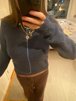 Mörkblå stickad tröja - Mysig mörkblå stickad tröja med croppad passform och långa ärmar. Tröjan har en enkel design utan synliga loggor och är gjord i ett fluffigt material som ger en avslappnad outfit.