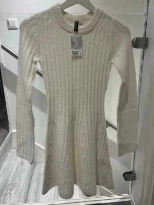 Vit stickad klänning från H&M, XXS - Mysig vit stickad klänning från H&M med ribbad struktur och lång ärm. Aldrig använt den. Prislappen sitter kvar. Storlek XXS💖