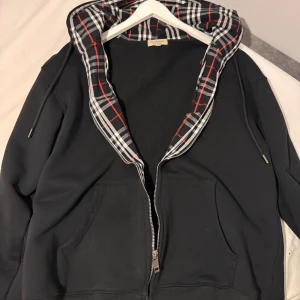 BURBERRY DRAGKEDJA  - En utav de bästa burberry zip upen på marknaden. Den är använd max 2-3 ggr och är i det bästa skicket, inga bemärkelser eller fel alls, fråga bara om bilder så får ni fler! Jättebra burberry och passar till alla säsonger 