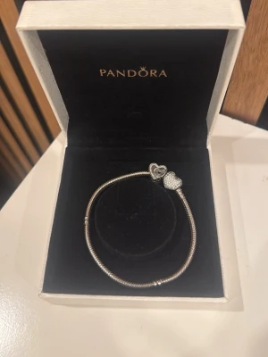Pandora armband - Säljer min Pandora armband med en berlock. Säljer pågrund av att jag bär mer silver och att den är lite stor på mig! Det är inga fel på den!! Fråga för flera bilder 