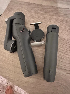 DJI OM gimbal 6 för smartphone - Säljer en svart DJI OM gimbal 6 för smartphone med magnetiskt fäste och tillhörande stativ. Perfekt för stabila videoinspelningar och smidig hantering. Tillverkad i plast och metall med ergonomiskt handtag och flera kontrollknappar.