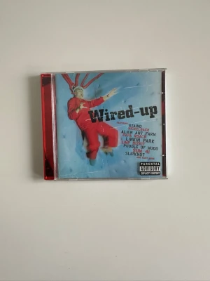 Wired-up samlings-CD med flera stora band och artister - Säljer en Wired-up samlings-CD med artister som Nickelback, Linkin Park, Alien Ant Farm och Slipknot. Omslaget är blått med en person i röd overall och CD-fodralet har röd kant. Perfekt för dig som gillar rock och nu-metal från tidigt 2000-tal. Mycket gott skick. 