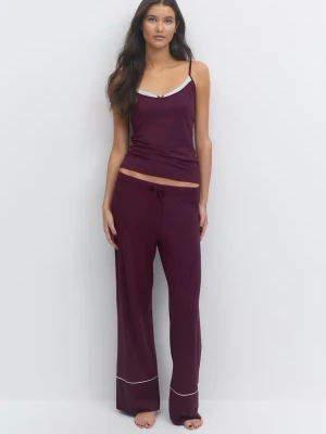 Gina Tricot Vinröd pyjamas med linne och byxa - Mysig vinröd pyjamas med ett linne med smala axelband och dekorativ vit kant samt matchande byxor med dragsko i midjan och vit piping vid benslut. Perfekt för avslappnade kvällar hemma. Materialet ser mjukt och stretchigt ut.
