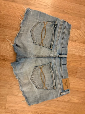 Ljusblå jeansshorts  - Abercrombie & fitch shorts. Dem är jätte lågmidjade😍 se bild hur dem sitter på mig som är 157cm lång. Stl är 24 men jag upplever dem som en stl större💗dem har små defekter på sidorna, men det är inget som stör och tror man enkelt kan sy igen dem små hålen 