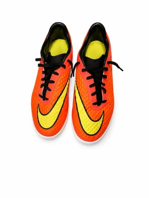 Nike orangea fotbollsskor - Säljer ett par grymma fotbollsskor från Nike i en riktigt snygg orange färg med stora gula swoosh-loggor på sidorna. Skorna har svart snörning och en texturerad ovandel i syntetmaterial för bättre bollkontroll. Perfekta för dig som vill sticka ut på planen!