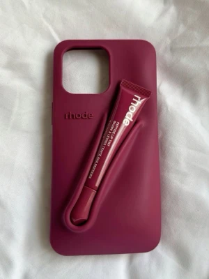 Rhode case + lip tint IPhone 13/14 - Säljer ett Rhode IPhone case i färg raspberry jelly med matchande lip tint. Passar till både IPhone 13 och 14! Nypris ca 750kr, väldigt bra skick 🩷