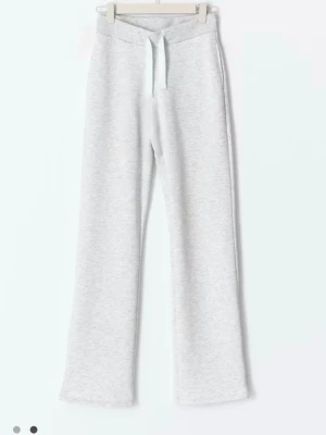 Ljusgrå mjukisbyxor med dragsko - Säljer ett par ljusgrå mjukisbyxor med raka ben och bred resår i midjan. Byxorna har en vit dragsko och är tillverkade i mjukt sweatshirtmaterial, perfekta för chill dagar. Passar dig som gillar enkel och clean stil.