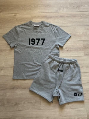 🩶Grått set med tryck 1977🩶 - Säljer ett grått set med t-shirt och shorts i mjukt bomullsmaterial. T-shirten har trycket '1977' i svart framtill och shortsen har samma tryck på benet. Shortsen har resår och dragsko i midjan för skön passform. Perfekt för chill dagar. Passar dig som har xs/ 165-175ish centimeter. Tar emot rimliga bud!!! Aldrig använt. Tags och påse kommer med