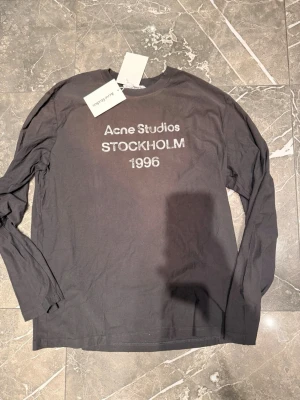 Svart långärmad t-shirt Acne Studios -  Helt ny Acne Studios långärmad tröja med prislappar kvar. Aldrig använd. Storlek L med en oversized passform som sitter baggy, särskilt vid armarna. Mjuk och bekväm med den klassiska Acne Studios Stockholm 1996-loggan på framsidan