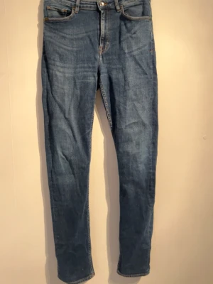 Blå slim fit jeans från tiger of sweden - Snygga blå slim fit jeans med klassisk femficksdesign och normal midja från tiger of sweden. Jeansen har en lätt tvättad look och raka ben. Perfekta för en avslappnad stil och passar till det mesta. Materialet är mjuk denim i bomull.